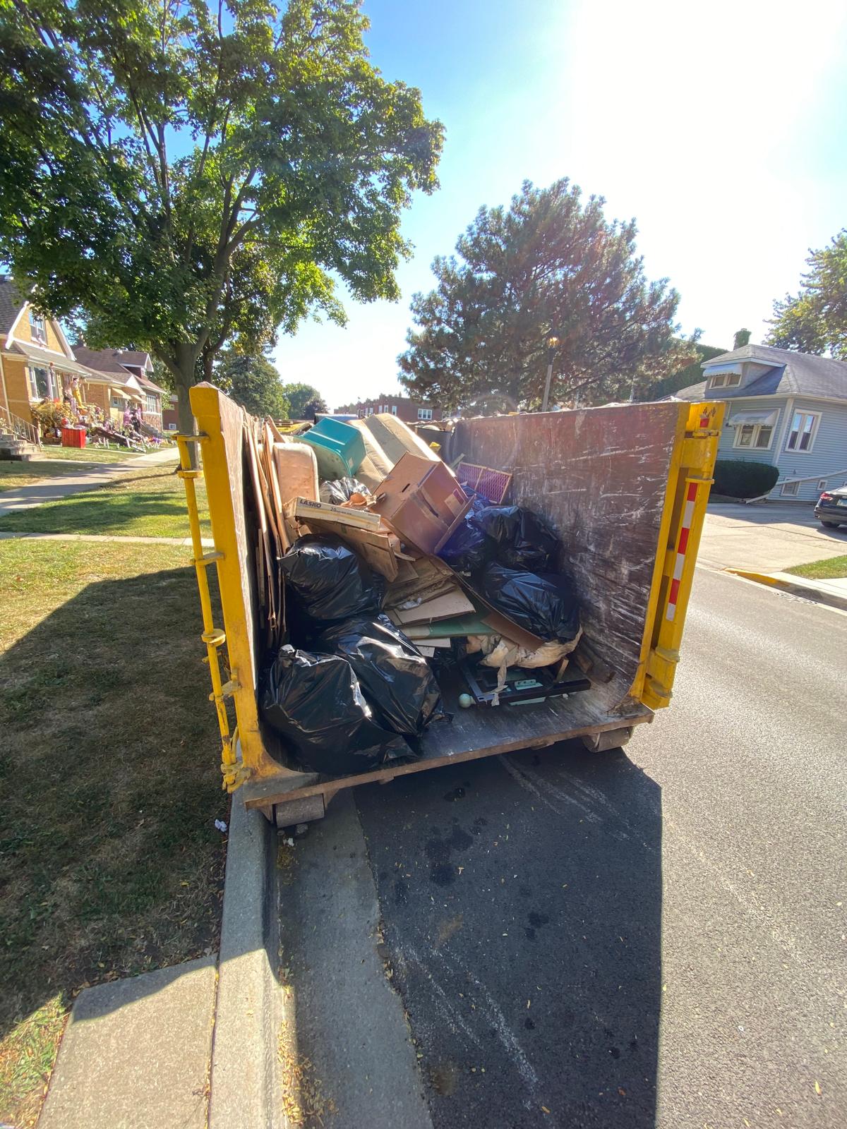 Dumpster loaded with removed items from hoarder cleanup project in Chicago suburbs